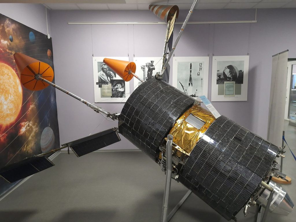 A communications satellite orbiting Earth with solar panels extended above the planet's curved horizon.