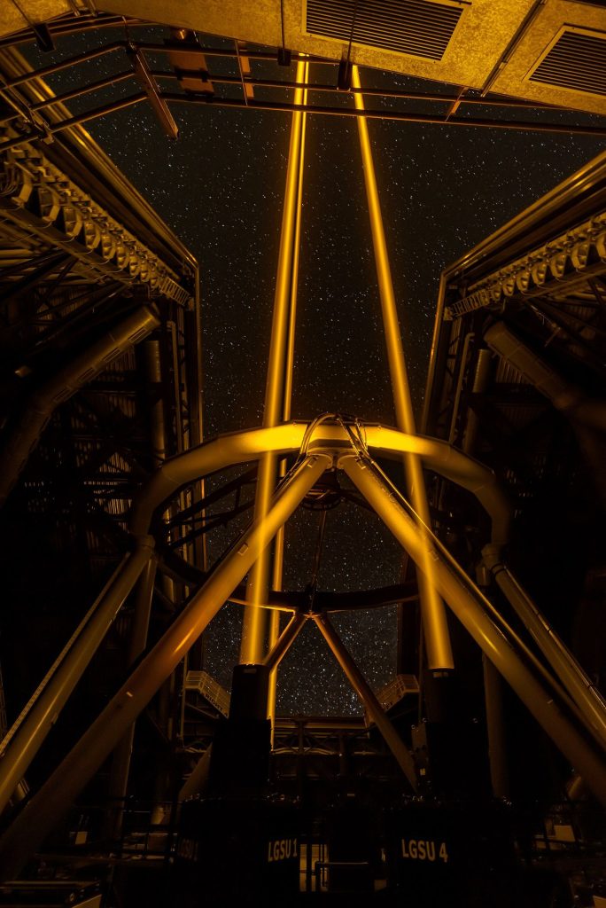 telescope silhouetted under a star-filled night sky